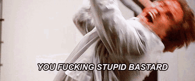 a man in a white shirt is screaming with the words you fucking stupid bastard below him