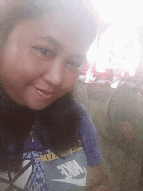 a woman wearing a blue nike shirt smiles for the camera