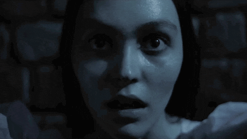 a blurry picture of a woman in a white shirt making a ghostly face .