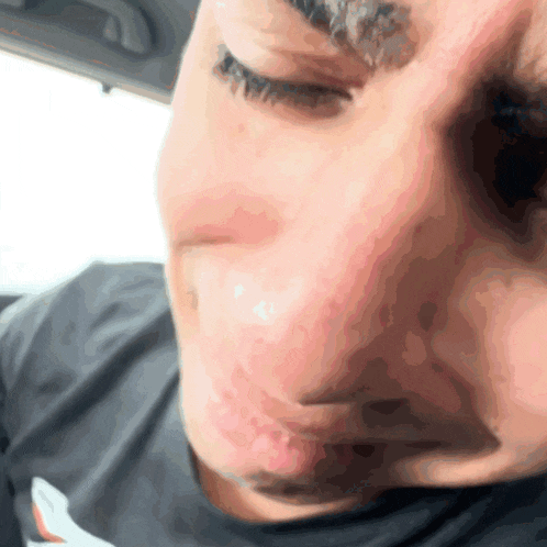 a close up of a man 's face with his eyes closed and a black shirt