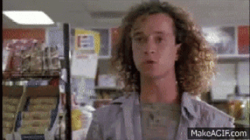 a man with curly hair is standing in a grocery store looking at something .