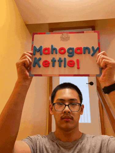 a man is holding up a sign that says mahogany kettle