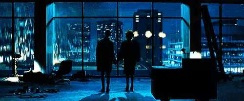 two people standing in front of a large window looking out at the city