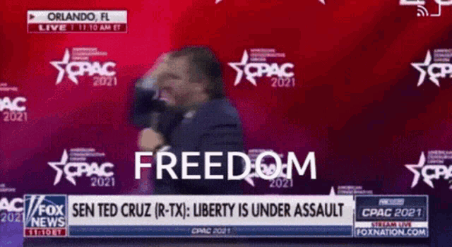 a man in a suit stands in front of a screen that says freedom on it