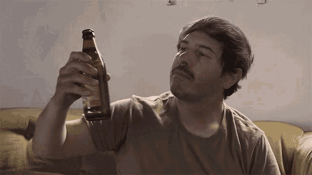 a man sitting on a couch holding a bottle of beer with a label that says ' amber ' on it