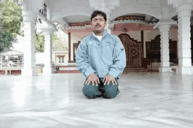 a man in a blue jacket is kneeling down in front of a temple