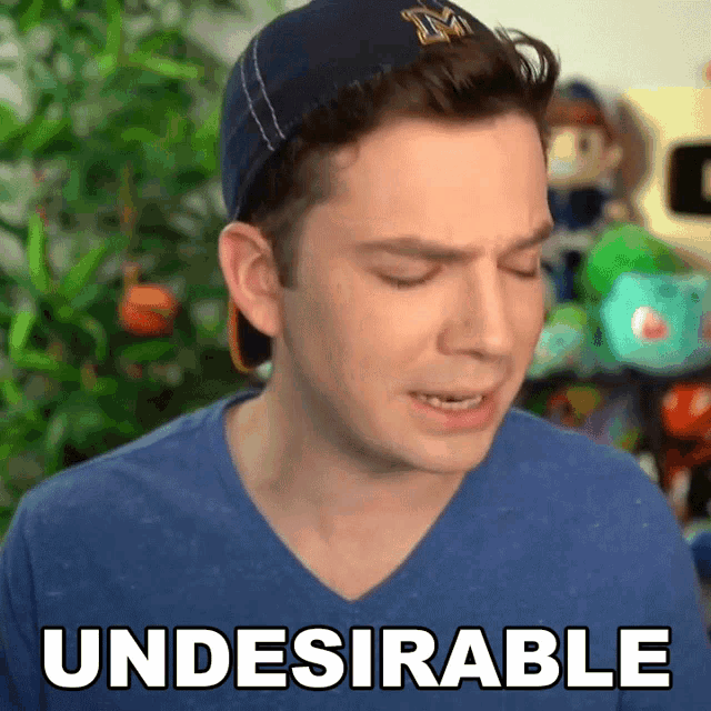 a man wearing a baseball cap and a blue shirt with the word undesirable on it