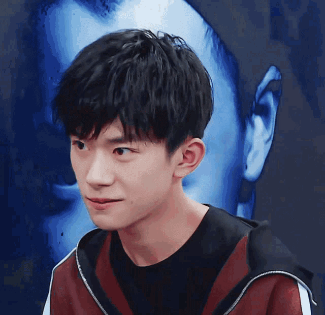 a close up of a young man 's face with a blue background behind him