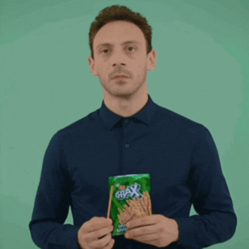 a man in a blue shirt is holding a bag of crackers in his hands
