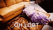 a woman in a purple dress is laying on the floor next to a couch and rug .