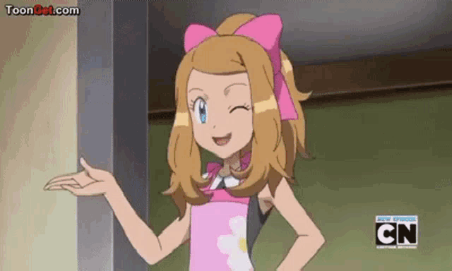 a girl in a pink dress with a pink bow on her head is standing next to a wall .