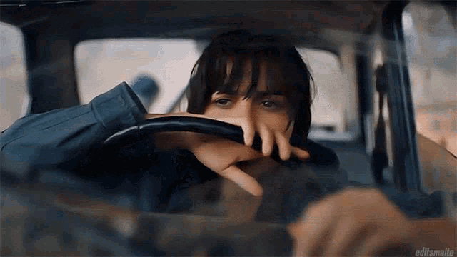 a person sitting in a car with their hand on the steering wheel ..