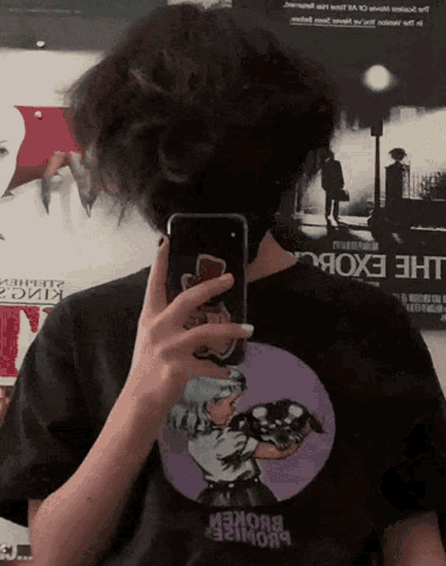 a person taking a picture of themselves with a phone and a t-shirt that says the exorcist
