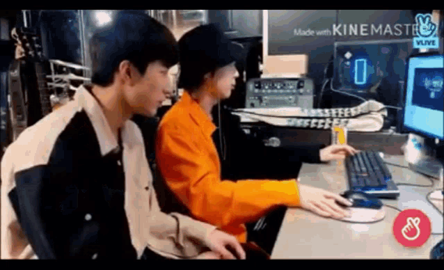 a couple of men are sitting at a desk with a computer .