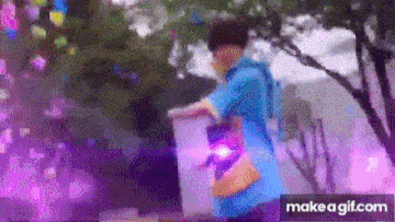 a person in a blue shirt is standing in front of a tree with purple lights coming out of it .