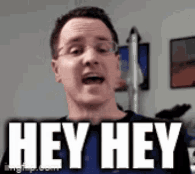 a man wearing glasses is making a funny face and saying `` hey hey '' .