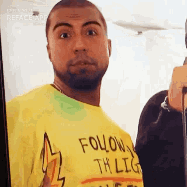 a man wearing a yellow t-shirt that says follow the light