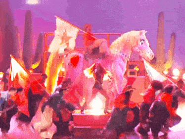 a group of people are dancing in front of a pink horse with a cowboy on it