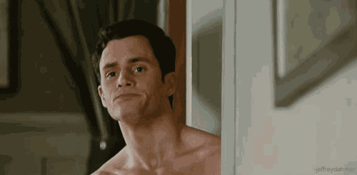 a shirtless man is leaning against a wall and looking at the camera .