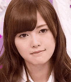 a close up of a woman 's face with brown hair and a white shirt .