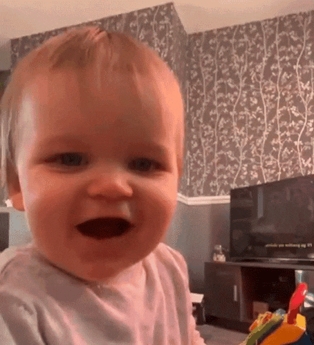 a baby is smiling in front of a tv in a living room .