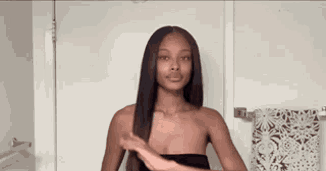 a woman is standing in front of a door in a bathroom holding her hair .