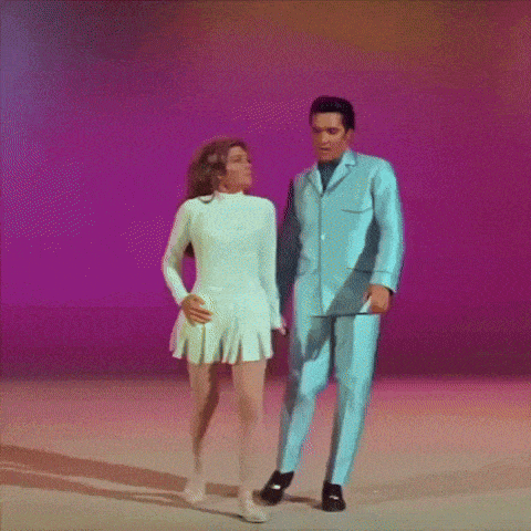 a man in a blue suit and a woman in a white dress are dancing together