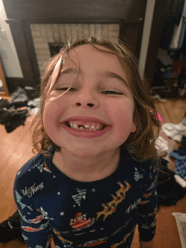 a little girl wearing a old navy pajama top smiles with her eyes closed