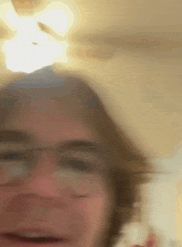 a blurry photo of a person 's face with a ceiling fan behind them