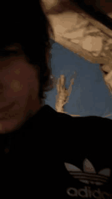 a close up of a person 's face wearing an adidas shirt