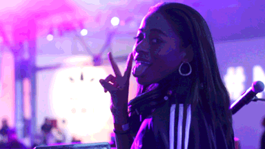 a woman wearing headphones giving a peace sign with her tongue out