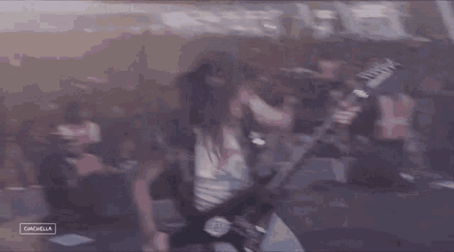 a man is playing a guitar on stage in front of a crowd at a concert .