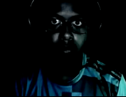 a man wearing headphones and a blue shirt has a scary face