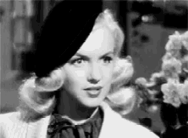 a black and white photo of a woman wearing a hat and a jacket .