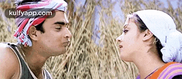 a man and a woman are kissing each other in a field of tall grass .