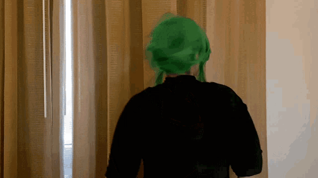 a person with green hair is standing in front of a window with curtains