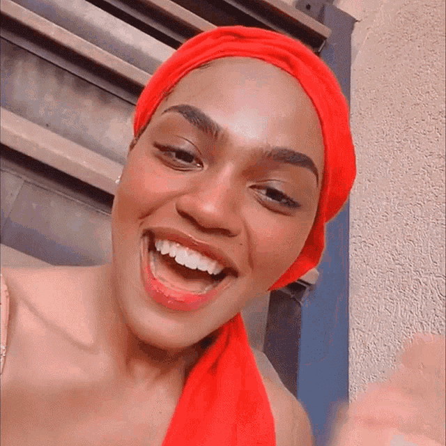 a woman wearing a red head scarf smiles with her mouth open