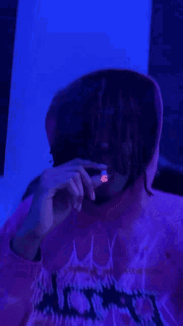 a person in a pink hoodie with a spider web on it smoking a cigarette