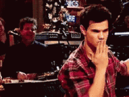 a man in a red plaid shirt covering his mouth with his hands