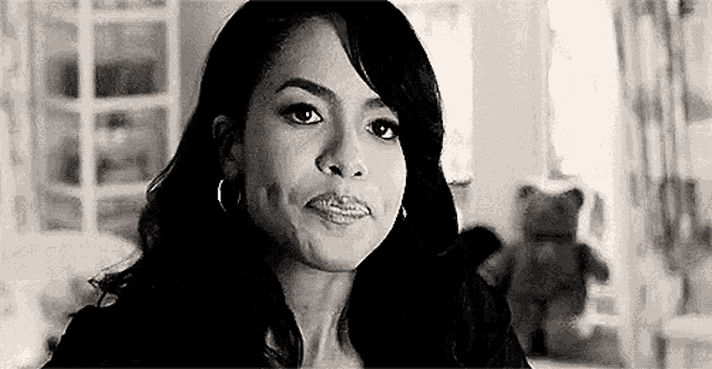 a black and white photo of a woman wearing hoop earrings looking at the camera .