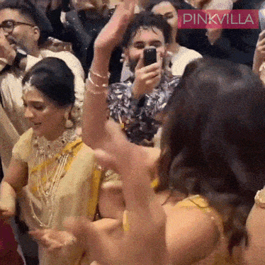 a man is taking a picture of a woman dancing in front of a crowd of people .