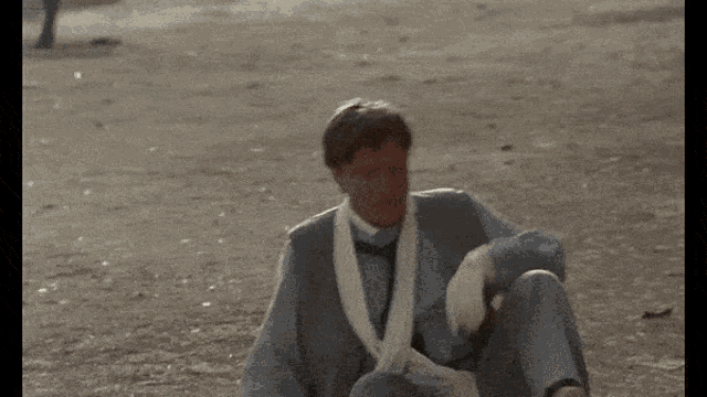 a man sits on the ground wearing gloves and a scarf