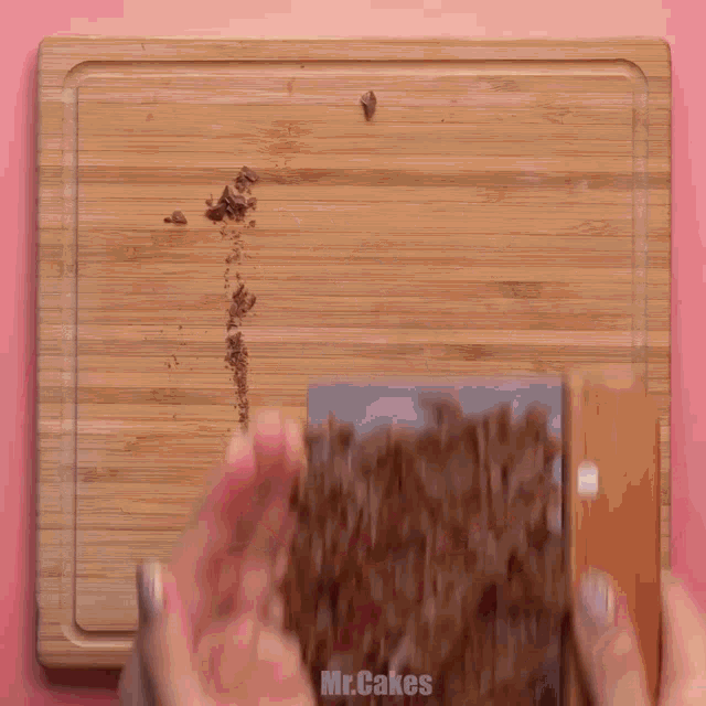 a wooden bowl filled with nuts on a pink surface