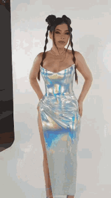 a woman in a silver dress is standing in front of a white background .