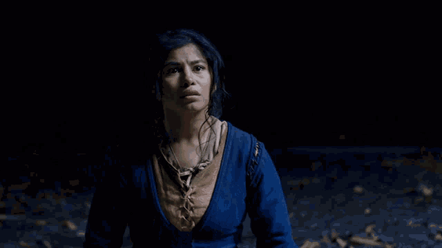 a woman in a blue sweater is looking at the camera in the dark