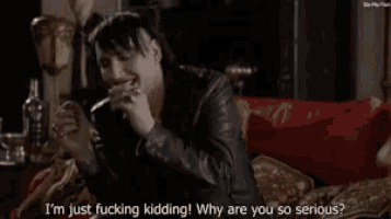 marilyn manson is sitting on a couch talking to a woman