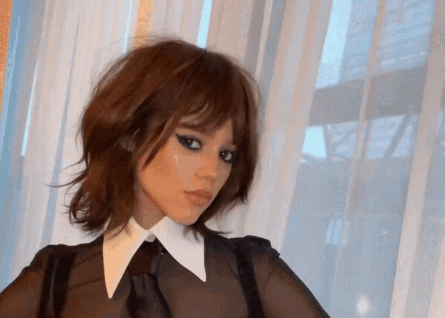 a woman with brown hair and a white collar