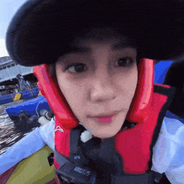 a man wearing a life jacket and a hat is looking at the camera