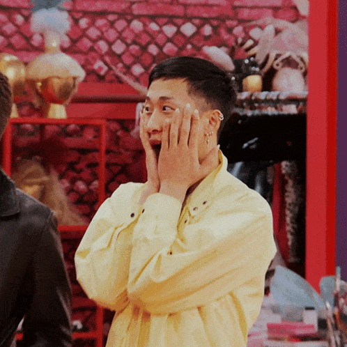 a man in a yellow shirt with his hands on his face