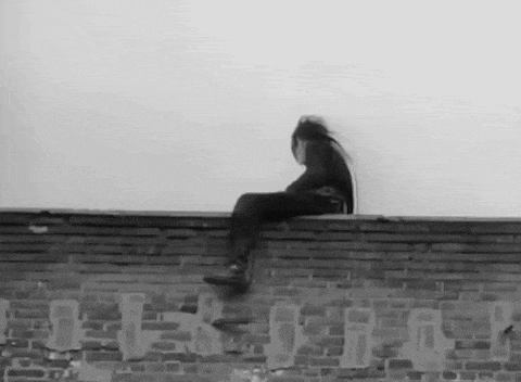 a person is sitting on the edge of a brick building .